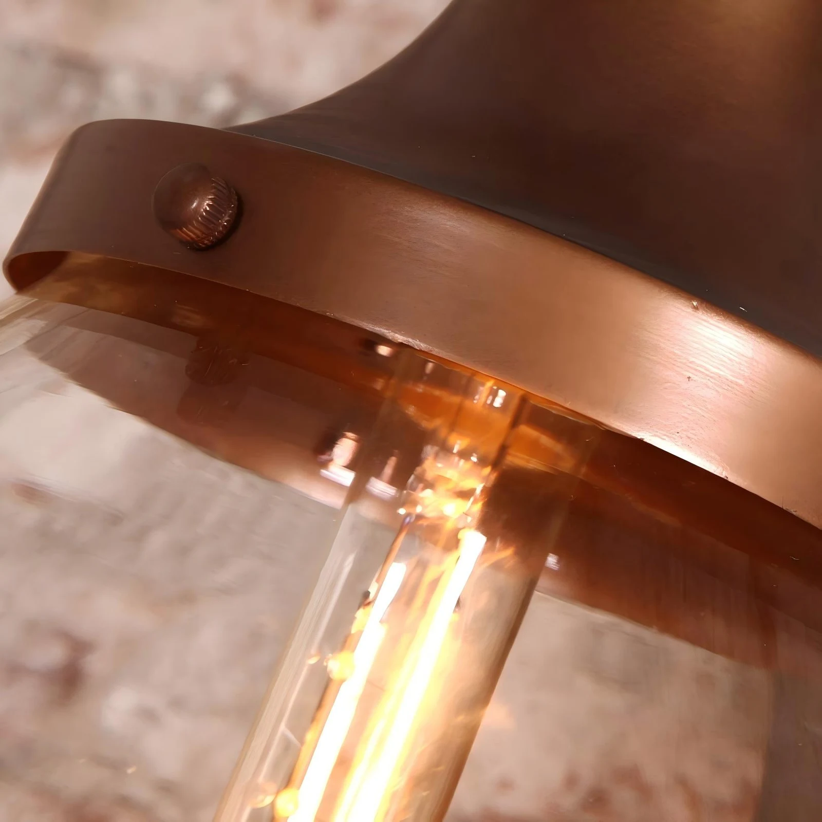 Cappuccio in ferro con finitura color rame e dettaglio della lampadina a luce calda